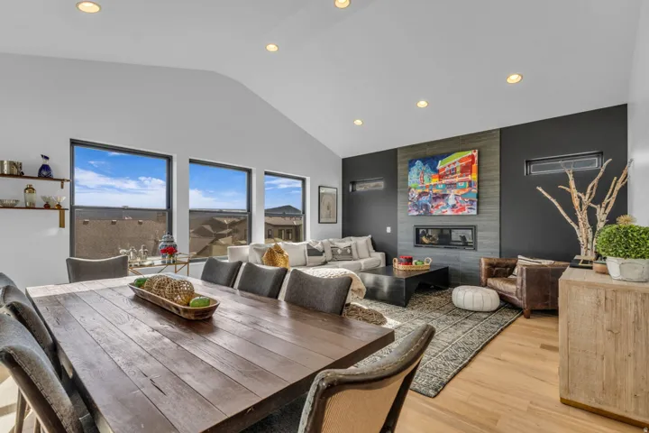 Vaulted ceilings with recessed lighting, large windows, a built-in fireplace, and wood-finish flooring