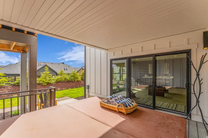 Covered patio with a built-in hot tub, black framed sliding glass doors, and a wall-mounted exterior light fixture