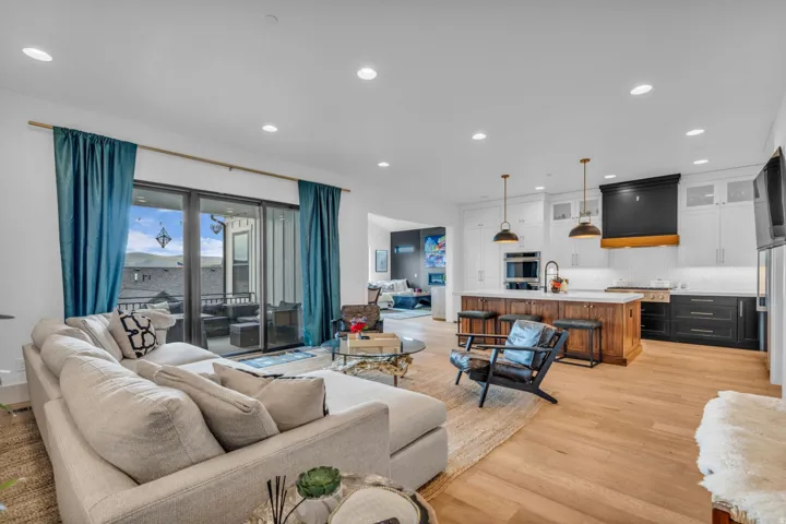 Open-concept living area featuring wood-finish flooring, recessed lighting, and a sliding glass door to an outdoor patio