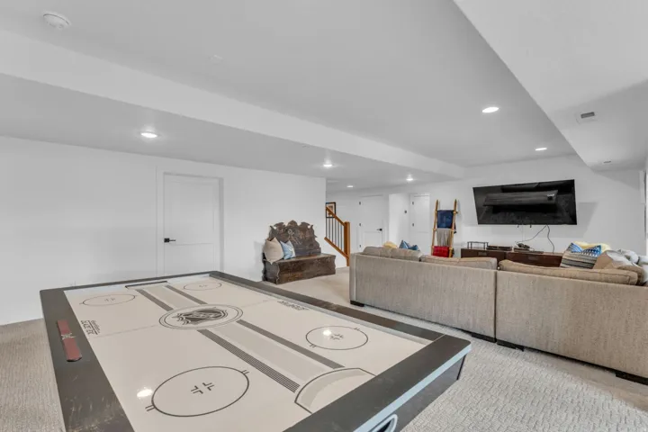 Recessed lighting, white walls, interior doors with matte black hardware, and carpet flooring