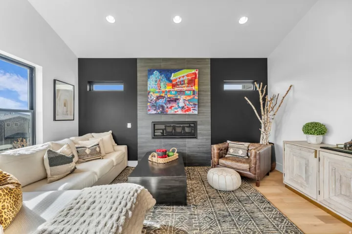 Recessed lighting, wood-finish flooring, and a modern fireplace with a tiled surround