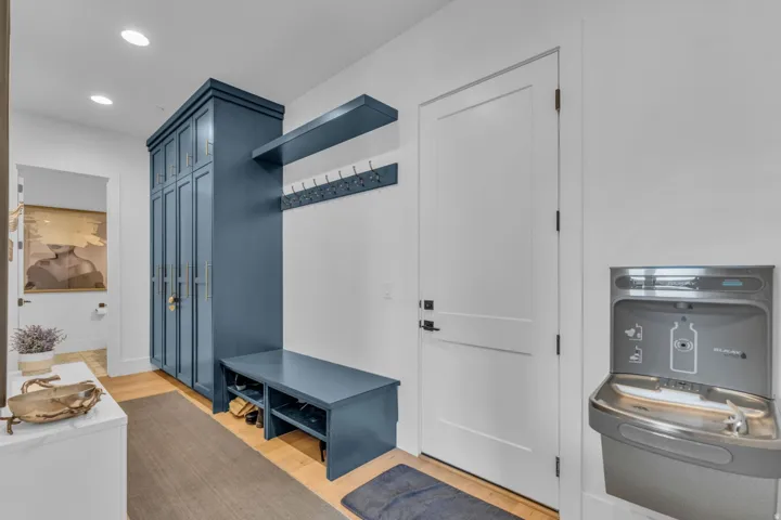 Built-in cabinetry with ample storage, integrated bench seating, and an overhead shelf with coat hooks