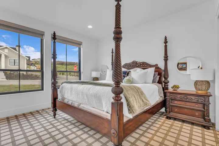 Dual windows with roller shades, recessed lighting, and patterned carpeting
