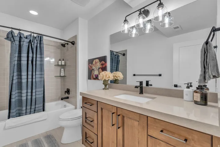 Built-in vanity with a single basin sink, matte black faucet, light-toned countertop, and wood-finish cabinetry