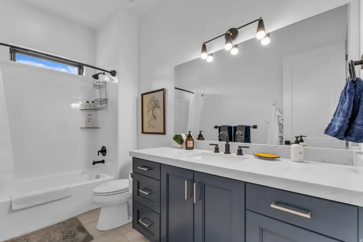 Bathroom featuring a dark wood vanity with a white countertop, large wall-mounted mirror, and a modern four-light fixture