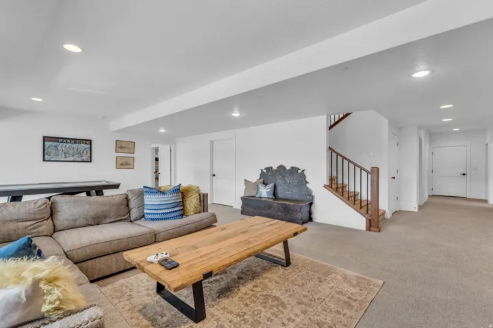 Recessed lighting, wood-finish stair treads, black metal stair balusters, and white interior doors