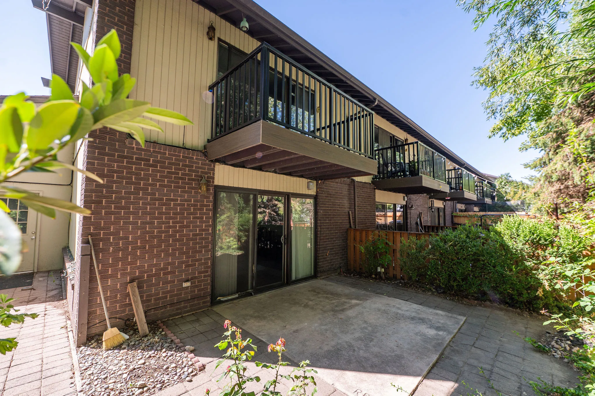 Brick and siding exterior with multiple private balconies, ground-level patio, and sliding glass doors