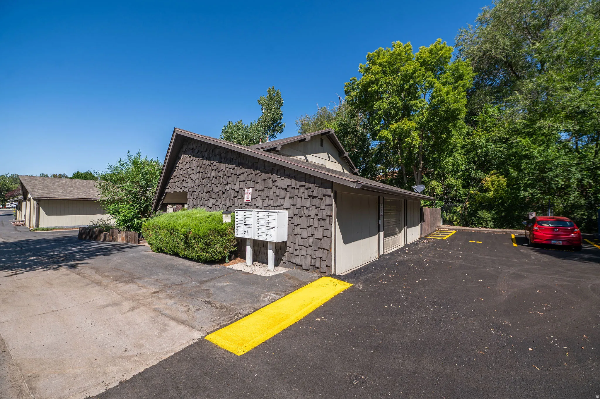 Wood-shingle exterior with a pitched roofline, alongside a paved parking area with designated spaces