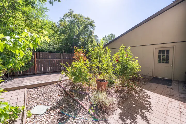 Private outdoor area featuring a wooden deck, mature landscaping, and a paver pathway