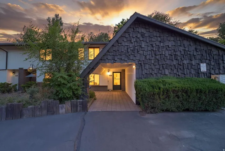 Asphalt driveway leading to a tiled entry and covered walkway