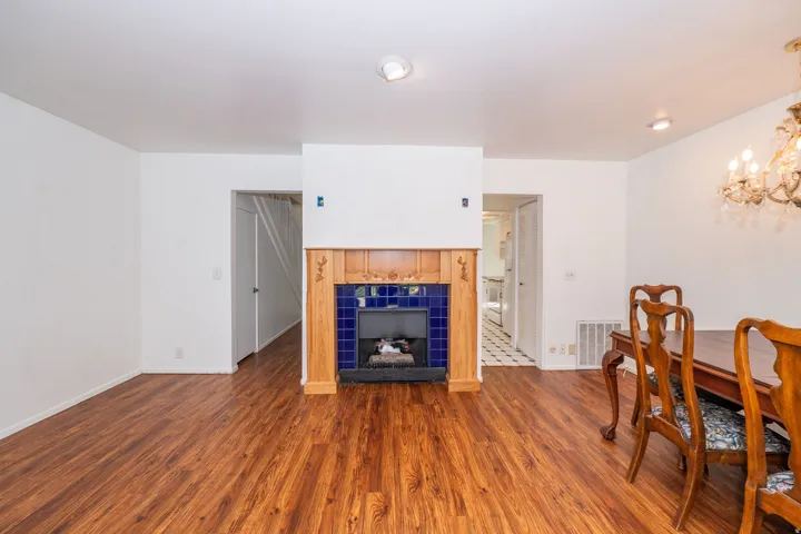 Wood-finish flooring throughout, featuring a fireplace with a wood mantle and blue tile surround, recessed lighting, and a decorative chandelier