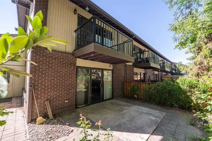 Brick and siding exterior with multiple private balconies, ground-level patio, and sliding glass doors
