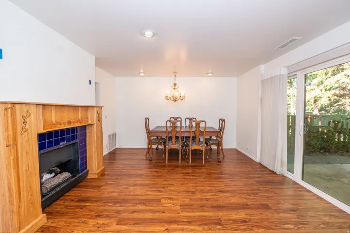 Wood-finish flooring throughout, a fireplace with a wood mantle and blue tile surround, recessed lighting, and a sliding glass door to outdoor space