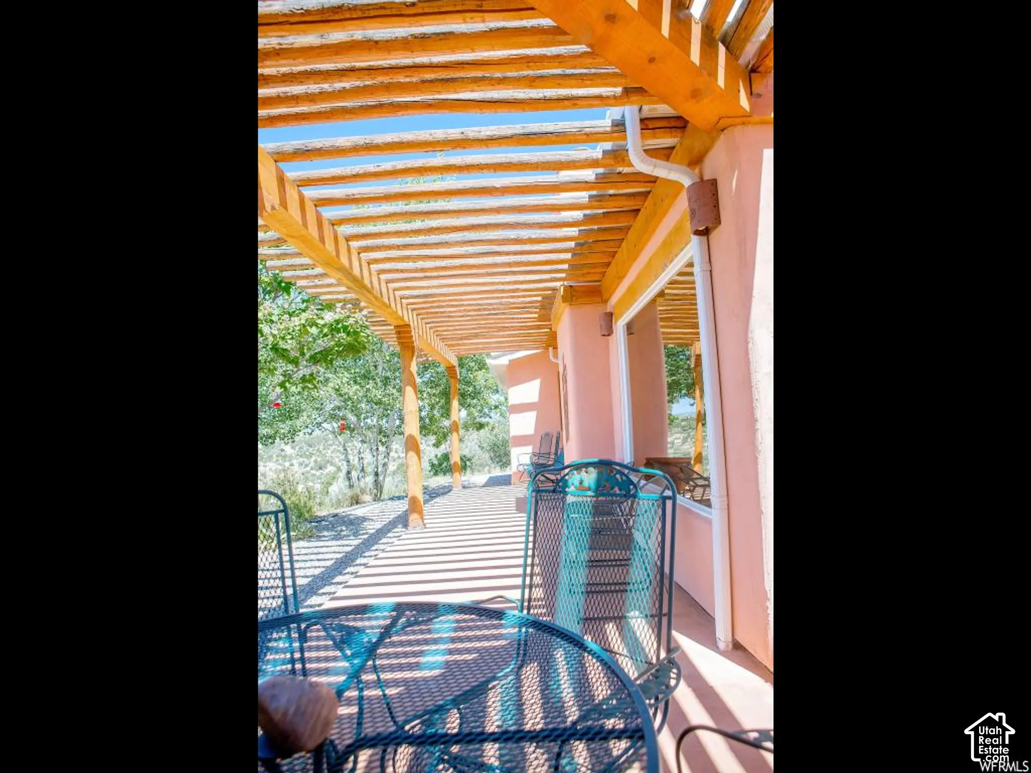 Covered patio with a wood pergola, stucco exterior, and a natural landscape