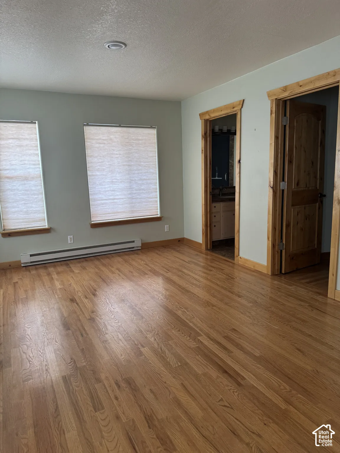 Wood-finish flooring, recessed ceiling lighting, light-toned walls, and wood-trimmed doorways