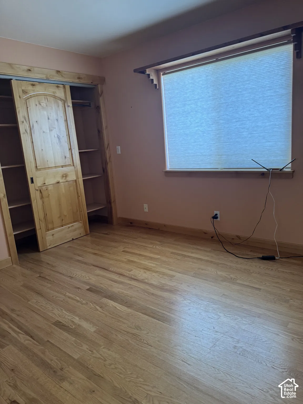 Hardwood flooring, wood-finish trim, built-in shelving, sliding barn door, and a window with blinds