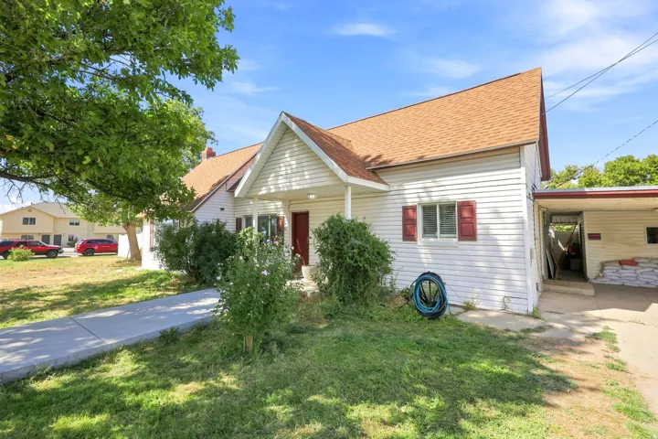 White siding exterior with a brown shingle roof, red shutters, and an attached carport