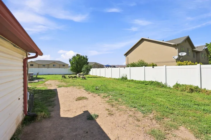 Expansive backyard featuring a white privacy fence, mature trees, and a substantial grassy area