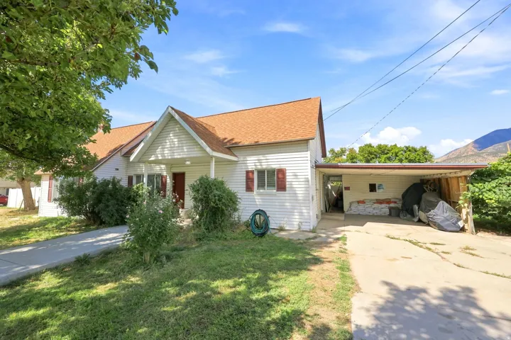 White siding exterior with a brown shingle roof, covered carport, and a concrete driveway