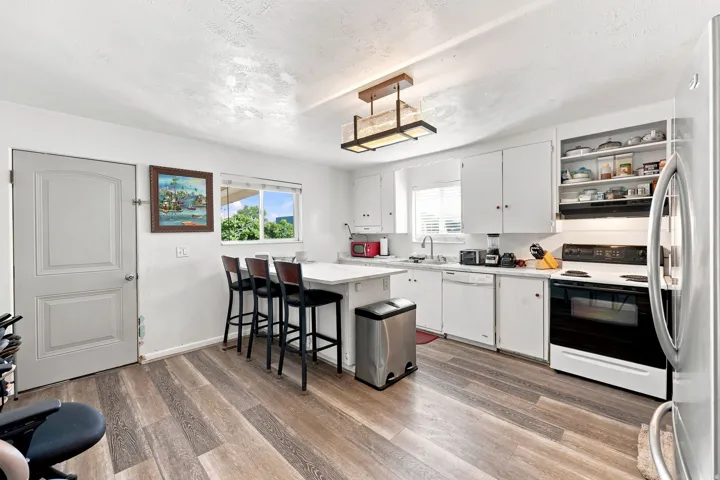 Kitchen featuring wood-finish flooring, white cabinetry, a single basin sink, and a built-in range