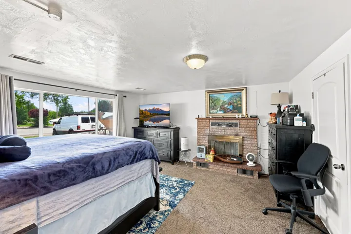 Brick fireplace with brass accents, large sliding glass door, white arched interior door, carpet flooring, and a flush mount ceiling light
