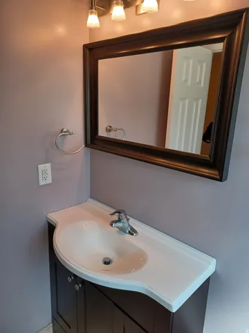 Vanity with integrated sink, chrome faucet, and dark wood-finish cabinetry