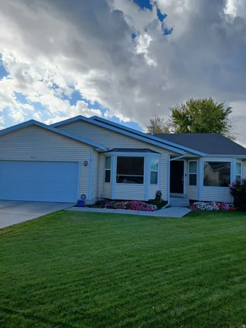 Ranch-style residence featuring a prominent two-car garage, bay window, and a neatly manicured lawn