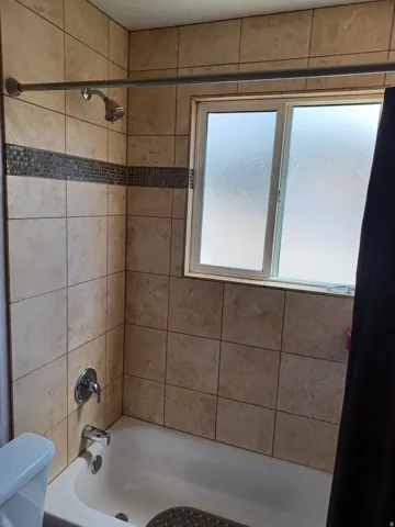 Tiled shower/tub combination featuring a decorative mosaic accent band