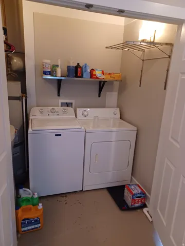 Dedicated laundry area featuring a washer and dryer, an elevated storage shelf, and a wall-mounted drying rack