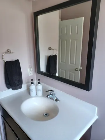 Vanity with an integrated basin, chrome faucet, and framed mirror