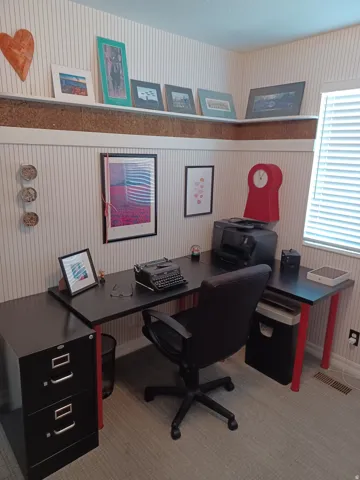 Built-in corner desk, striped wallpaper, corner shelving, and window with blinds