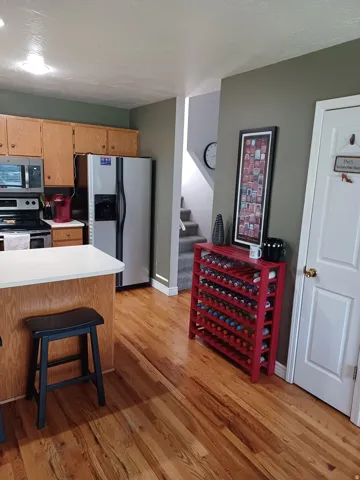 Hardwood flooring throughout, kitchen with wood cabinetry, stainless steel refrigerator, and a built-in microwave
