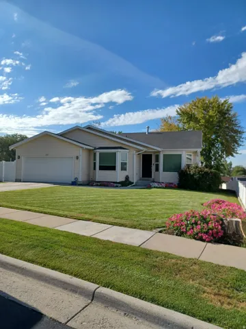 Single-story residence featuring a two-car garage, bay window, landscaped front yard, and concrete pathway