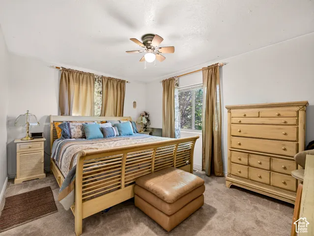 Bedroom opposite of primary bedroom, carpeted flooring, window with natural light, and a ceiling fan with integrated lighting