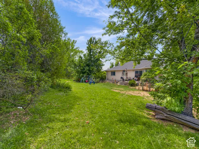Expansive green space with mature trees and a rear patio