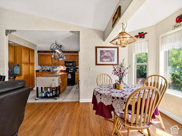 View of secondary dining, kitchen, LVP flooring, vaulted ceiling, and recessed windows with natural light
