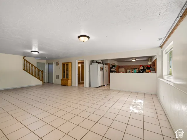 Expansive tiled flooring throughout, built-in counter space, and a wood-finish staircase with railing