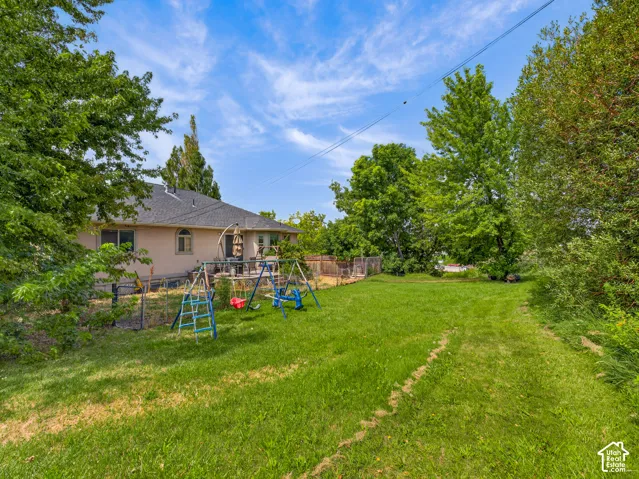 Expansive backyard featuring a large grass area and mature trees