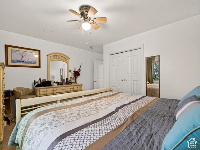 Bedroom opposite of primary bedroom, ceiling fan, white walls, double-door closet, ceiling-mounted lighting, and carpeted flooring
