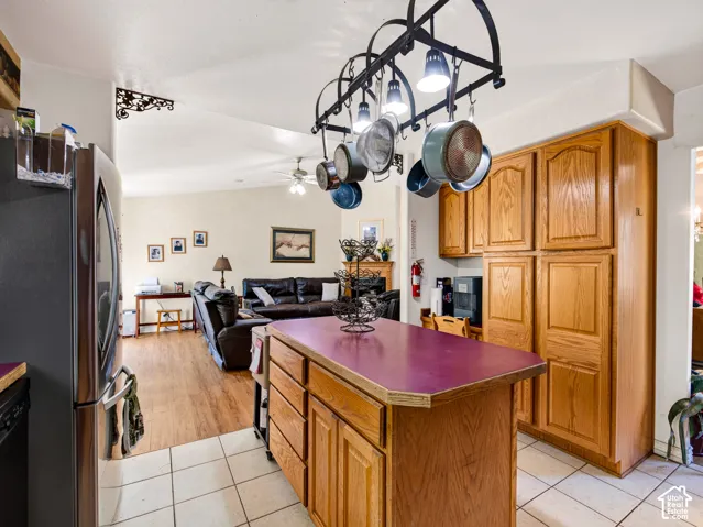 Kitchen with wood cabinetry, a central island with a contrasting countertop, and a pot rack overhead