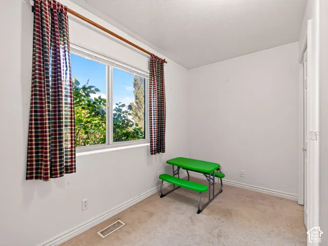 Front bedroom with double-pane window providing abundant natural light, neutral wall paint, and carpeting