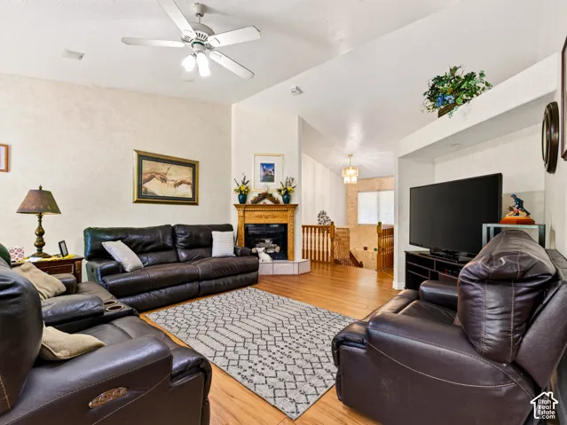 Family room with vaulted ceiling, a ceiling fan, LVP flooring, corner fireplace with a wooden mantel