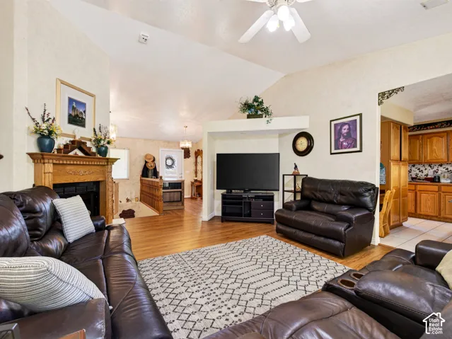 Family room with vaulted ceiling, LVP flooring, ceiling fan, wood mantle, built-in fireplace