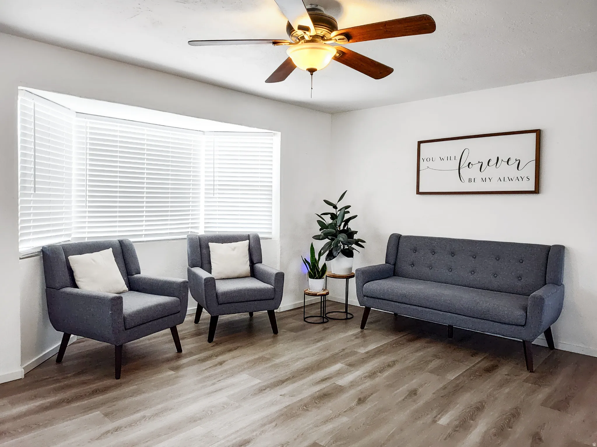 Recessed bay window with blinds, wood-finish flooring, ceiling fan with integrated lighting, and white wall finishes