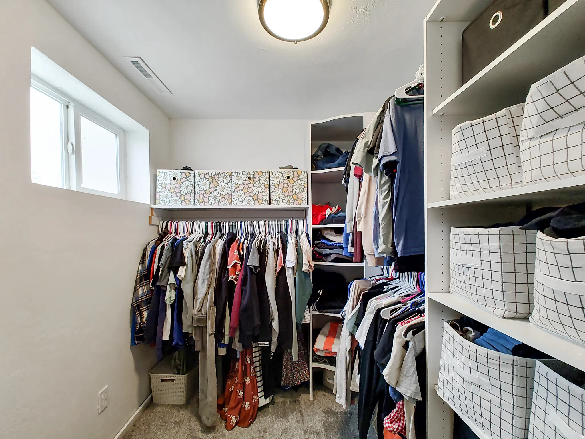Built-in closet shelving system with multiple hanging rods, dedicated storage shelves, and a high-set horizontal window