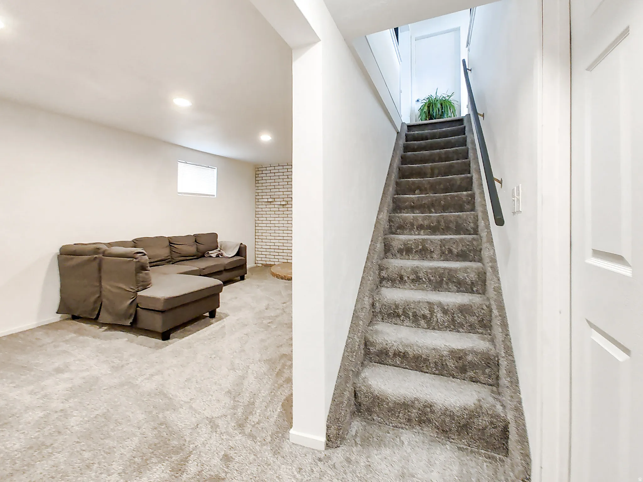 Carpeted staircase with black handrail, recessed lighting, and white interior doors
