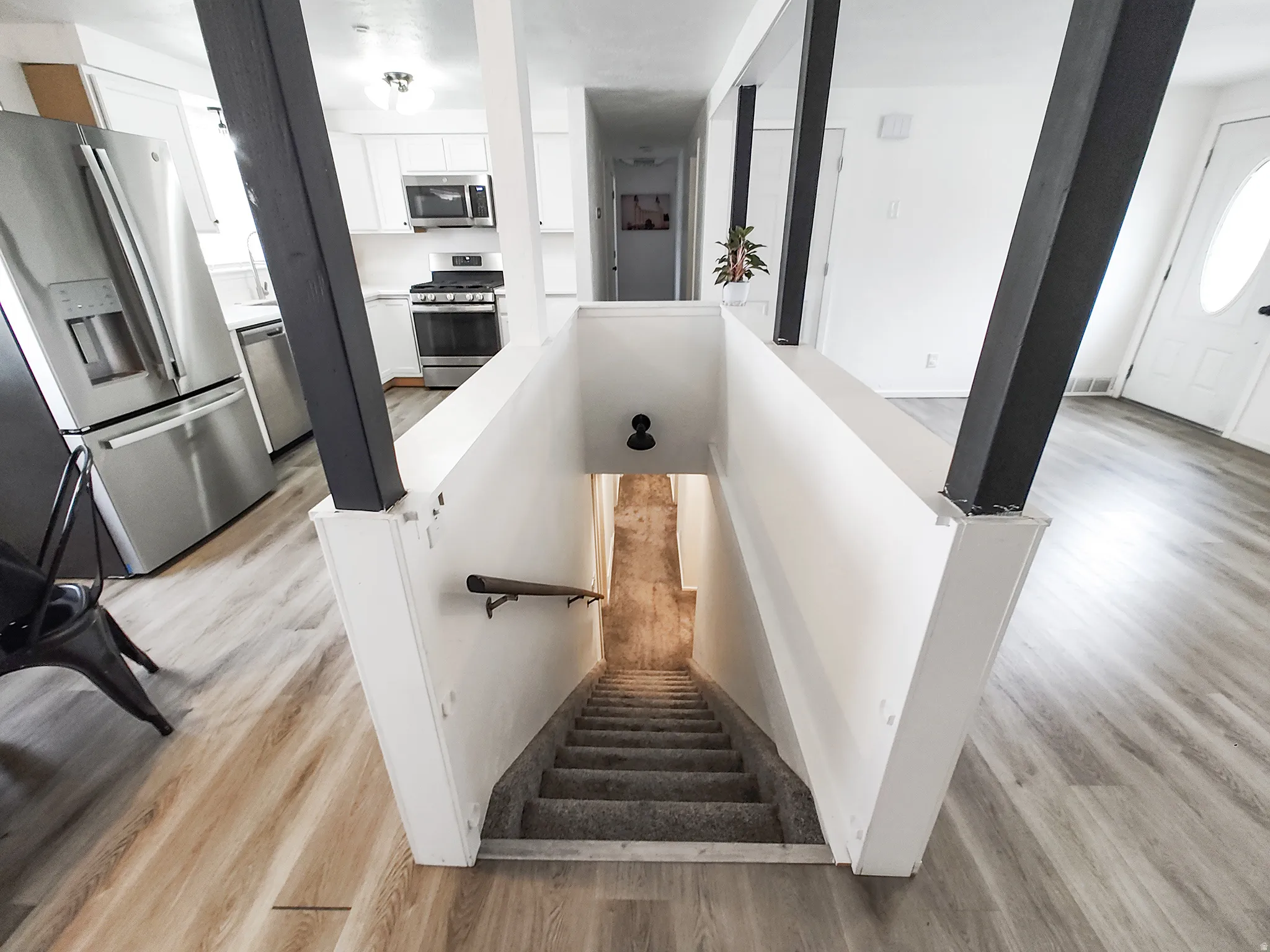Modern kitchen with stainless steel appliances, white cabinetry, and wood-finish flooring