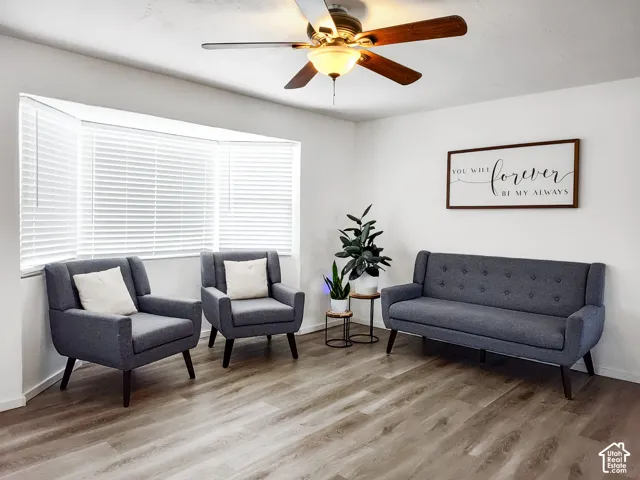 Recessed bay window with blinds, wood-finish flooring, ceiling fan with integrated lighting, and white wall finishes
