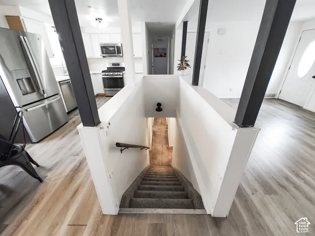 Modern kitchen with stainless steel appliances, white cabinetry, and wood-finish flooring