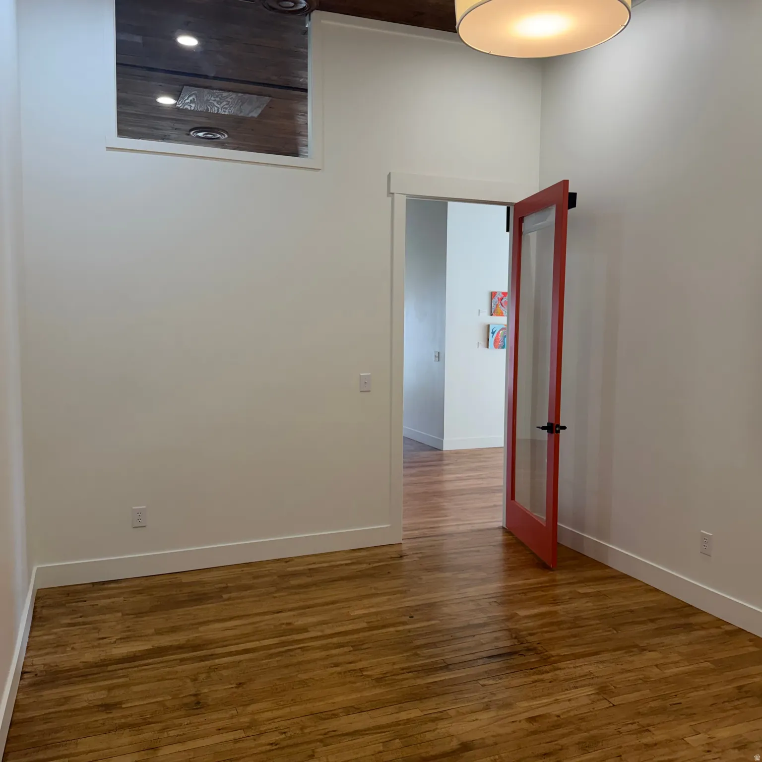 Wood-finish flooring throughout, high ceilings, transom window, and a modern glass-paneled door